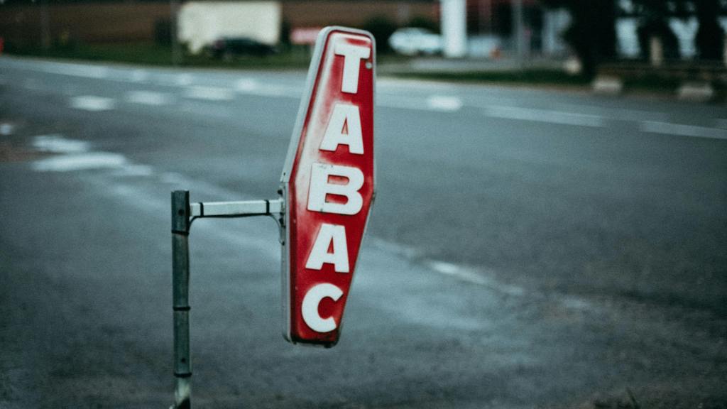 A vintage 'Tabac' sign on a street with blurred background, captured at dusk.