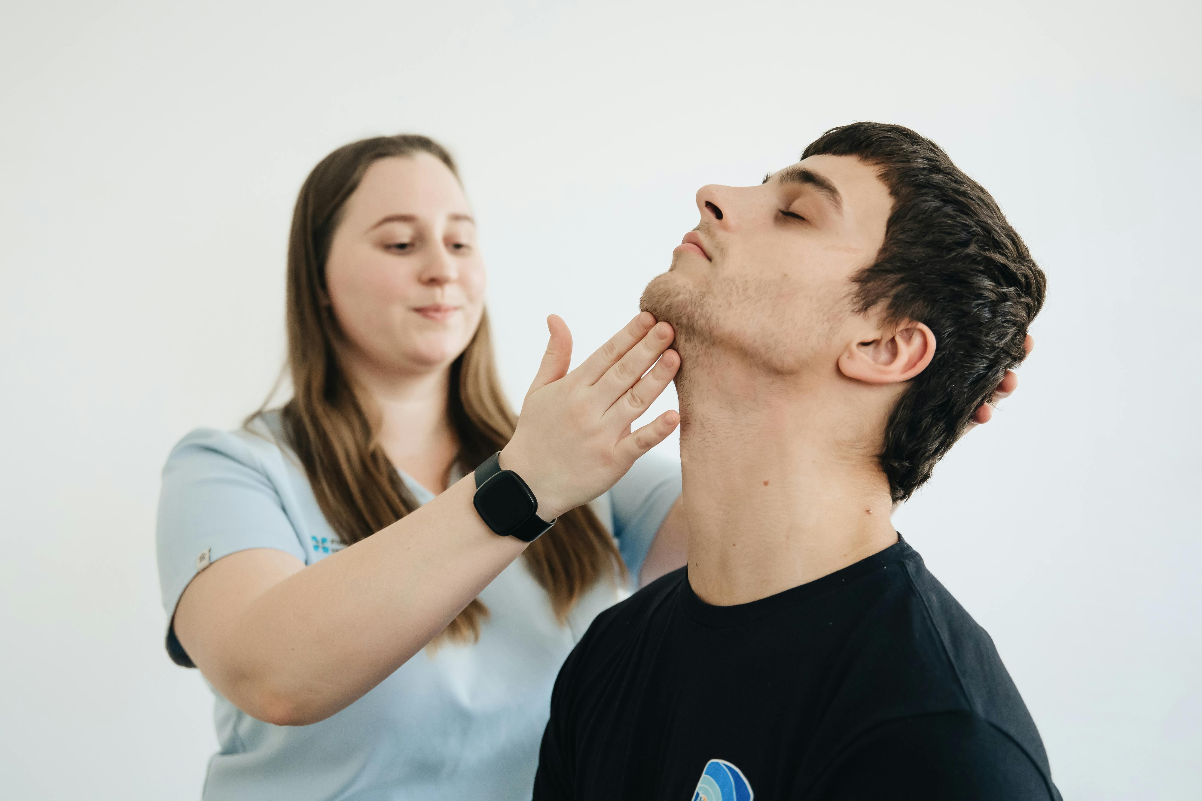 A physiotherapist performs therapy on a male patient's neck in Vilnius clinic.